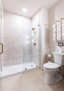 a white bathroom with a shower and a toilet at Hollyhock Suite 404 in Louisville
