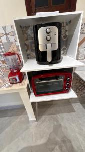 a microwave sitting on top of a white shelf at Pousada Charmosa Lua Nova Pipa - Chales com Jacuzzi e Hidro in Pipa