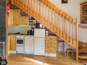a kitchen with white appliances and a wooden staircase at Holiday Home Yllästokka 5 by Interhome in Ylläsjärvi