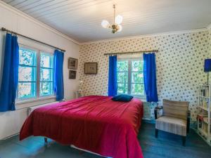 a bedroom with a red bed and blue curtains at Holiday Home Piispasen torppa by Interhome in Alastaro