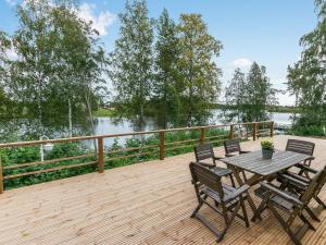 a wooden deck with a table and chairs and a lake at Holiday Home Salmiranta by Interhome in Jämijärvi