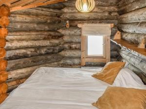 a bed in a log cabin with a window at Holiday Home Kelokota by Interhome in Salla