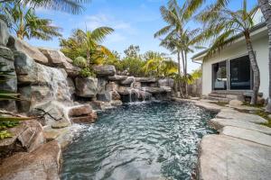 a backyard pool with a waterfall and a rock wall at Encinitas Shores - Beachfront, Ocean View & Patio in Encinitas