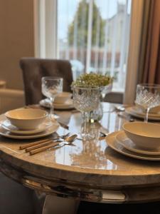 a wooden table with plates and silverware on it at Modern 2BR Cottage Flat in Bellshill