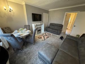 a living room with a couch and a table and chairs at Modern 2BR Cottage Flat in Bellshill