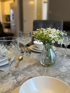a table with a vase of flowers on a table with glasses at Modern 2BR Cottage Flat in Bellshill +10 photos