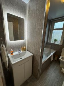 a bathroom with a sink and a mirror and a tub at Modern 2BR Cottage Flat in Bellshill
