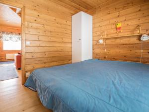 a bedroom with a blue bed in a wooden wall at Holiday Home Lehtotuvat e by Interhome in Kotila