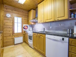 a kitchen with wooden cabinets and a white dishwasher at Holiday Home Lehtotuvat e by Interhome in Kotila