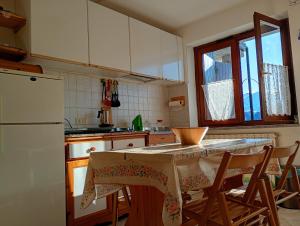 a kitchen with a table with chairs and a white refrigerator at Casa Lory in Prato Nevoso