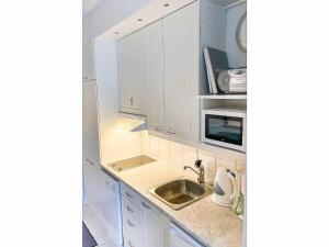 a white kitchen with a sink and a microwave at Holiday Home Levi star 1502 by Interhome in Levi
