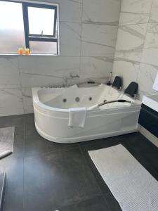a white bath tub in a bathroom with a window at Kbros Guesthouse in Polokwane +51 photos
