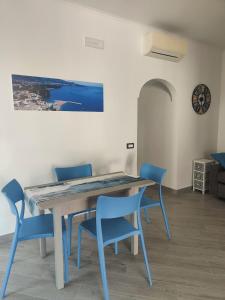 a dining room table with blue chairs and a painting at 80062 Cute House in Meta