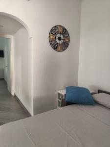 a bedroom with a clock on a white wall at 80062 Cute House in Meta