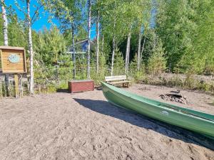 a green boat sitting on the sand next to a wooden bench at Holiday Home Nummentähti by Interhome in Tammela