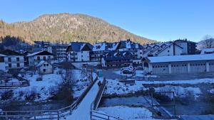 a town with snow covered buildings and a mountain at SkiLift Tarvisio Apartment Free Parking in Tarvisio