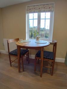 a wooden table with two chairs and a window at River View at Silver River in Cadamstown