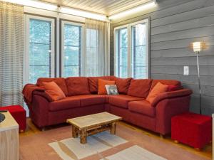 a red couch in a living room with windows at Holiday Home Pulkka 1 by Interhome in Salla