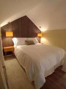 a bedroom with a large white bed and two lamps at River View at Silver River in Cadamstown +4 photos