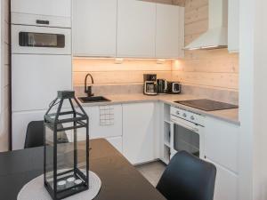 a kitchen with white cabinets and a table with chairs at Holiday Home Kitkanvee 1 by Interhome in Kuusamo