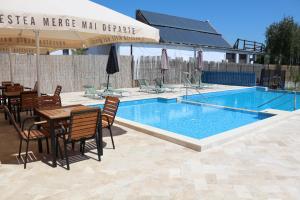a swimming pool with a table and chairs next to at Pensiunea Ataman in Murighiol