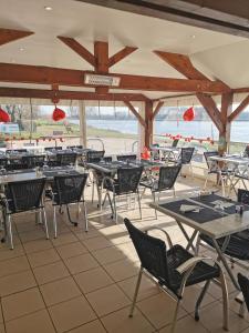 an empty restaurant with tables and chairs and the ocean at CAMPING LES HERLEQUINS in Losne