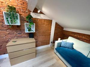 a bedroom with a brick wall and a bed and a dresser at Capitole Hyper-centre, Mezzanine & confort in Toulouse