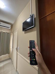 a person holding a remote control in a room at Hotel Executive Uberaba in Uberaba