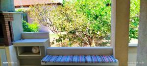 a bench on a balcony with a tree in the background at Zach's house in Nea Roda