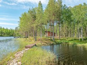 a cabin in the woods next to a lake at Holiday Home Jolmalompolo by Interhome in Raanujärvi