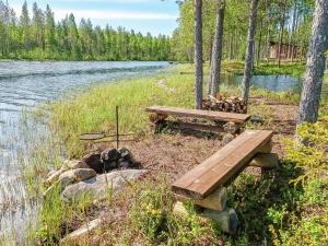 a picnic table and fire pit next to a river at Holiday Home Jolmalompolo by Interhome in Raanujärvi