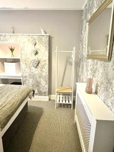a bedroom with a bed and a mirror and a chair at Small Cosy Flat in Helensburgh
