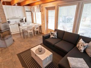 a living room with a black couch and a kitchen at Holiday Home Arha by Interhome in Äkäslompolo