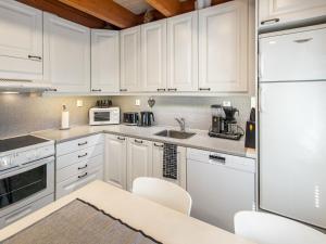 a kitchen with white cabinets and a white refrigerator at Holiday Home Arha by Interhome in Äkäslompolo