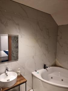 a bathroom with a white tub and a sink at COni sobe Kragujevac in Kragujevac