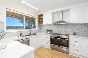 a white kitchen with white cabinets and a window at Absolute Birubi Beachfront in Anna Bay