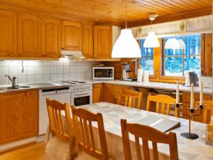 a kitchen with wooden cabinets and a table with chairs at Holiday Home Kuusenkolo by Interhome in Pyhätunturi