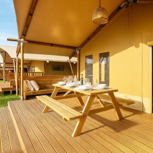 a wooden picnic table with glasses on a patio at Glamping Il Poderino in Cecina