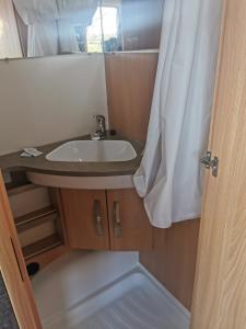 a bathroom with a sink and a shower curtain at CAMPING LES HERLEQUINS in Losne +28 photos