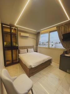 a bedroom with a bed and a chair and a window at Cloud pyramids view inn in ‘Ezbet `Abd el-Ḥamîd