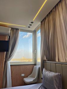 a bedroom with a window and a bed and a chair at Cloud pyramids view inn in ‘Ezbet `Abd el-Ḥamîd