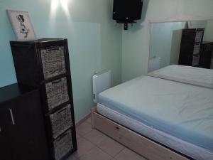a small bedroom with a bed and a dresser and a television at Appartement avec vue sur le Lac in Sainte-Croix-de-Verdon