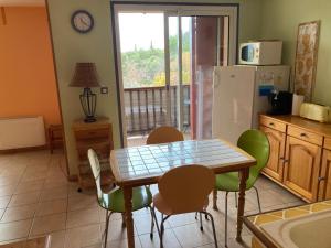 a kitchen with a table and chairs and a refrigerator at Appartement avec vue sur le Lac in Sainte-Croix-de-Verdon
