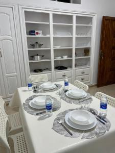 a white table with plates and water bottles on it at Spacious Family Apartment in Er Rachidia