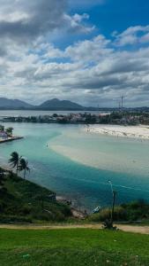 a beach with a bunch of people in the water at Sol e Sal Suítes Aconchegantes in Saquarema