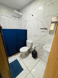 a bathroom with a toilet and a blue shower curtain at Sol e Sal Suítes Aconchegantes in Saquarema
