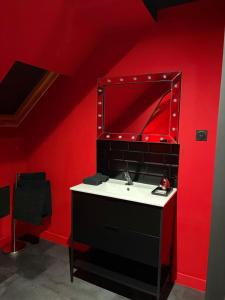 ein Badezimmer mit Waschbecken und einer roten Wand in der Unterkunft Spa2Luxe - L Interdite in Saint-Quentin