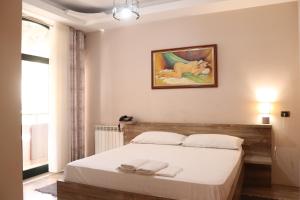 ein Schlafzimmer mit einem Bett und einem Gemälde an der Wand in der Unterkunft Hotel Sfinks Elbasan Albania in Elbasan