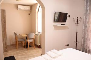 ein Zimmer mit einem Tisch und einem Fernseher an der Wand in der Unterkunft Hotel Sfinks Elbasan Albania in Elbasan