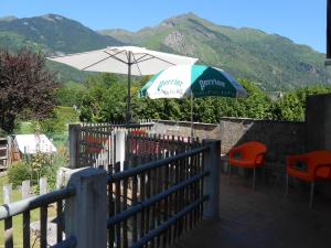 a patio with an umbrella and two chairs and a table with an umbrella at location Mirande 3 chamb 8 couchages 9 rue de soupon in Laruns